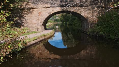 drone footage of a canal with a stone built bridge set in hebden bridge, yorkshire england