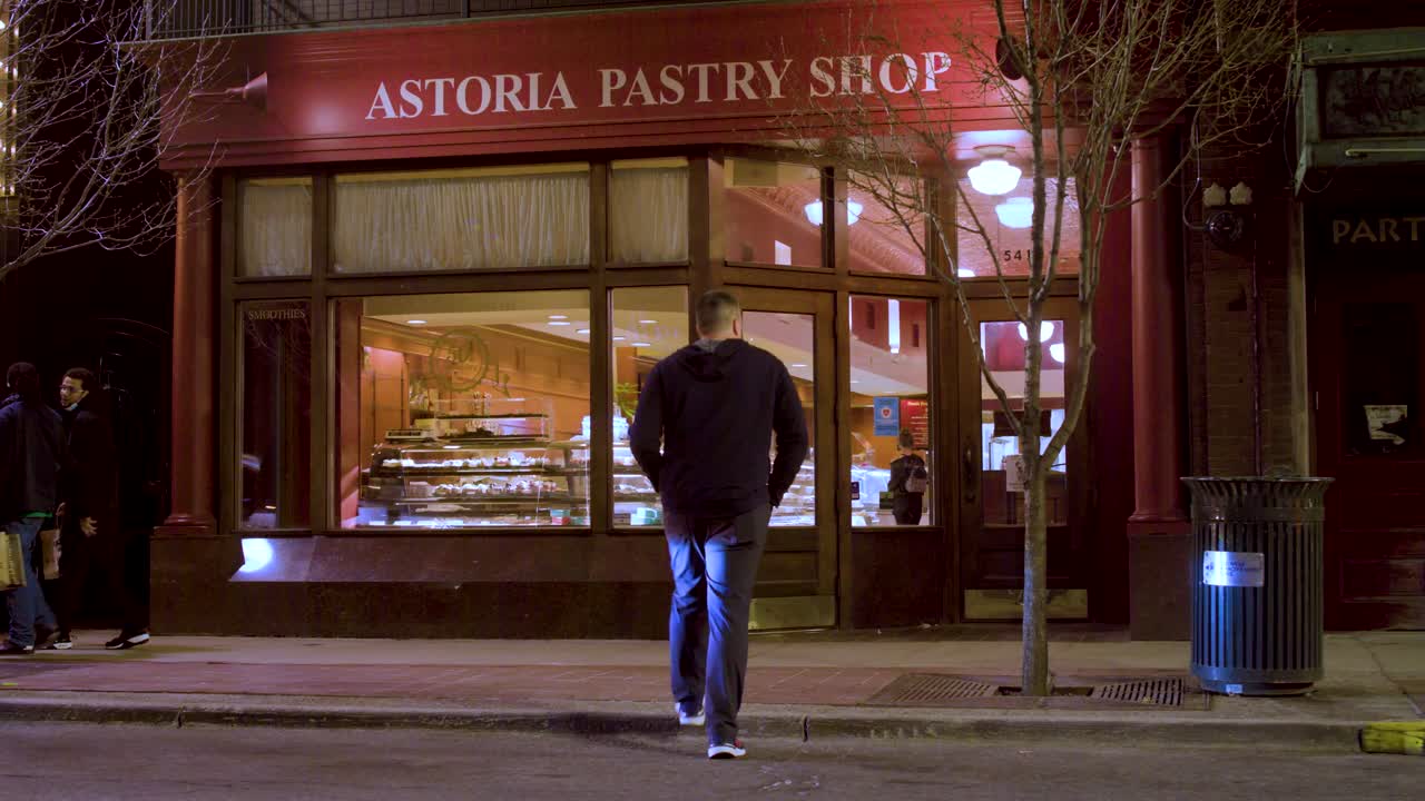 Un uomo cammina attraverso la strada verso una pasticceria