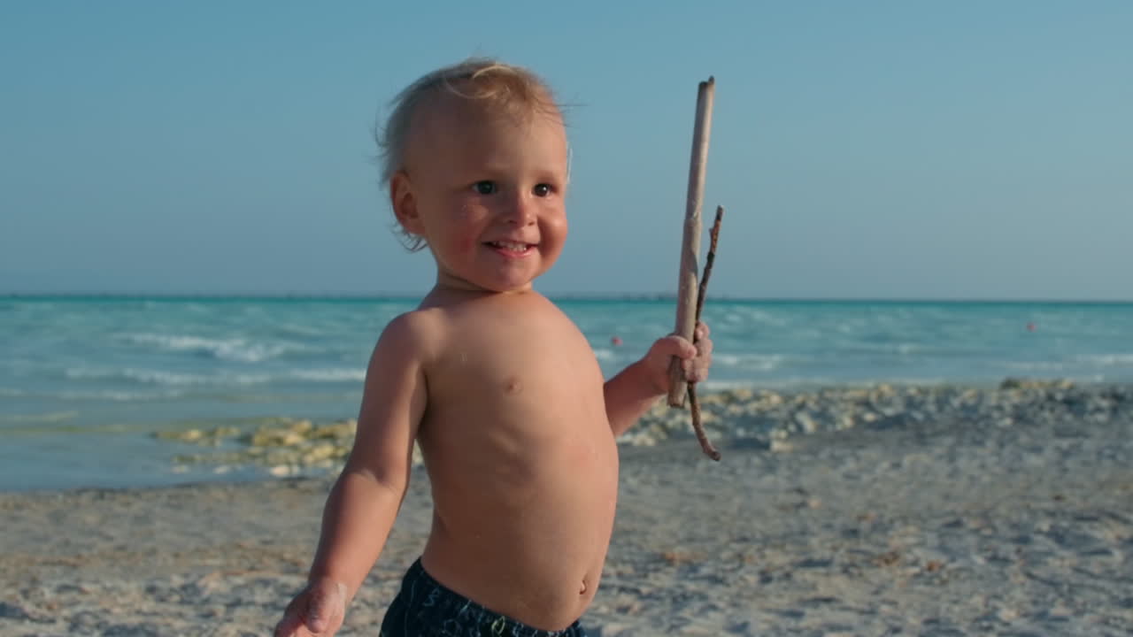 Bambino felice che si rilassa in riva al mare. Bambino sorridente che si gode una giornata di sole in spiaggia.