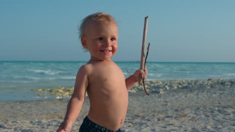 happy baby boy relaxing at seashore. smiling child enjoying sunny day at beach.