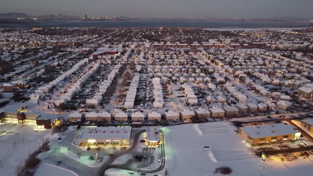 Aerial: residential area and cityscape at night with snow in St-Constant, Quebec, Canada, pull out drone shot