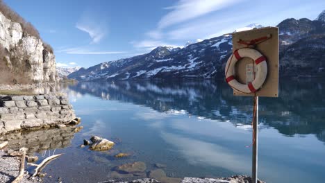 red, white life belt on a pole in a stunning winter mountain lake panorama in switzerland