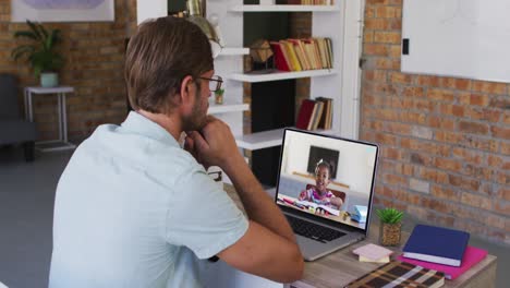Caucasian-male-teacher-having-a-video-call-with-school-girl-on-laptop-at-school