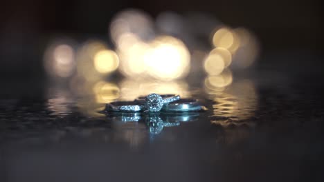 close-up rack focus to wedding rings on ice with lights in the background