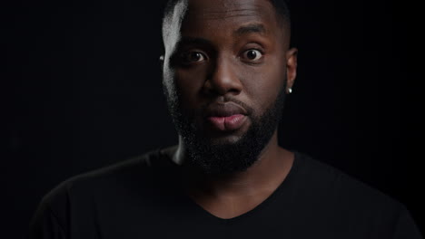 Euphoric-afro-guy-looking-at-camera-indoors.-Male-person-saying-wow-in-studio