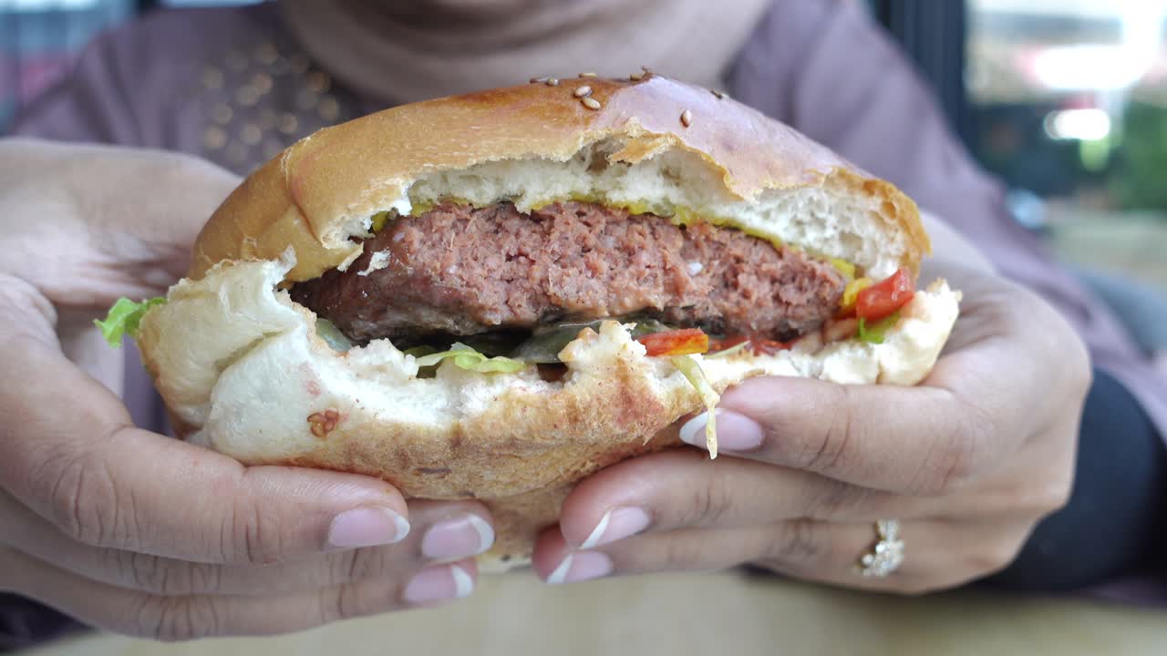 mujer sosteniendo una hamburguesa a base de plantas