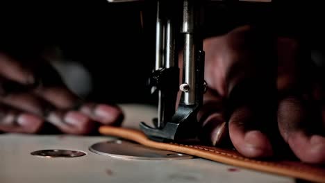 black man using a sewing machine to sew leather straps