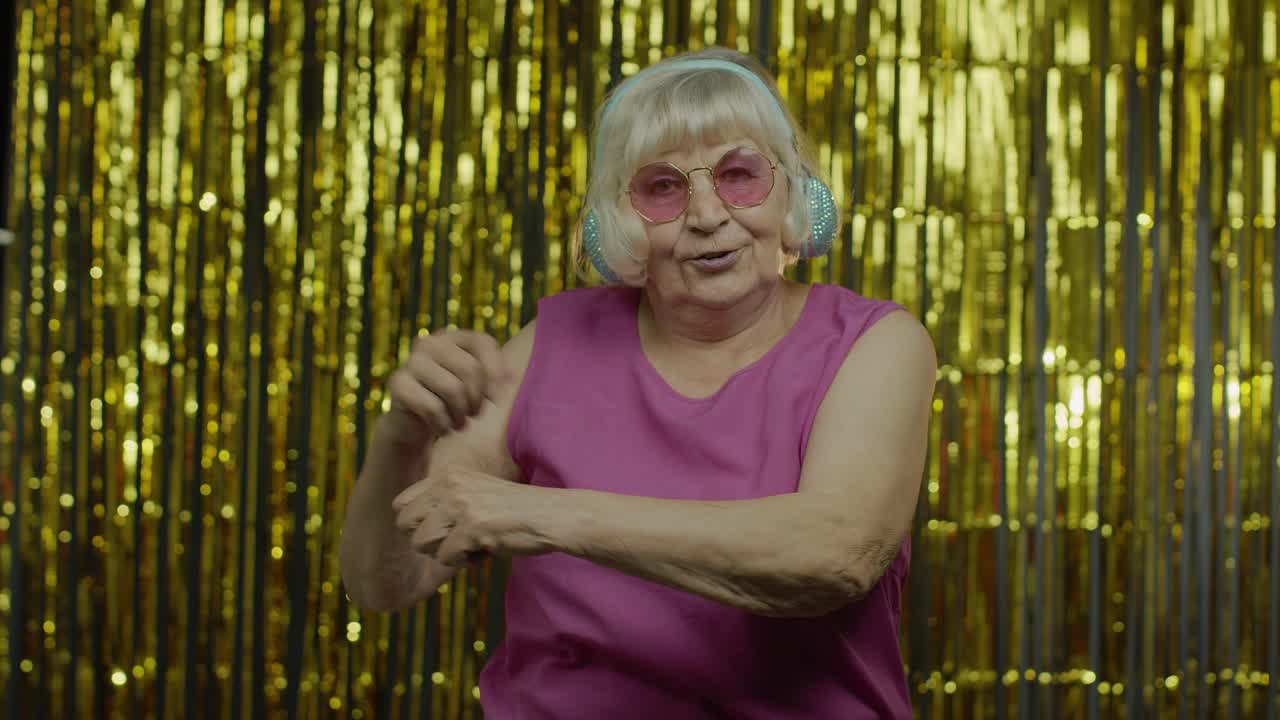 Mujer mayor baila, escucha música con auriculares. Relajándose, disfrutando, divirtiéndose, sonriendo.