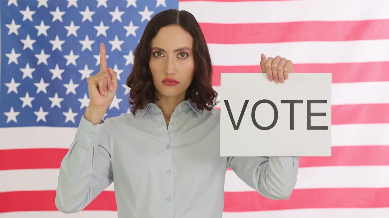 Woman holding 'VOTE' sign in front of American flag