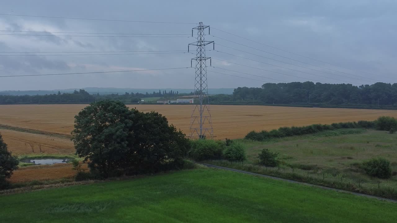 Electricity steel pylon high voltage wires in countryside agricultural farm field aerial view early morning low angle slow right orbit