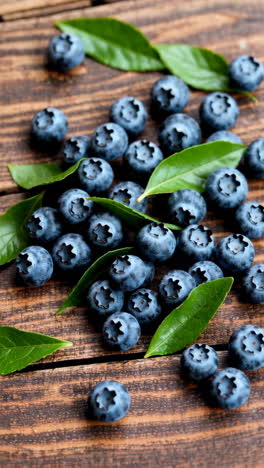 fresh blueberries with leaves on wooden surface