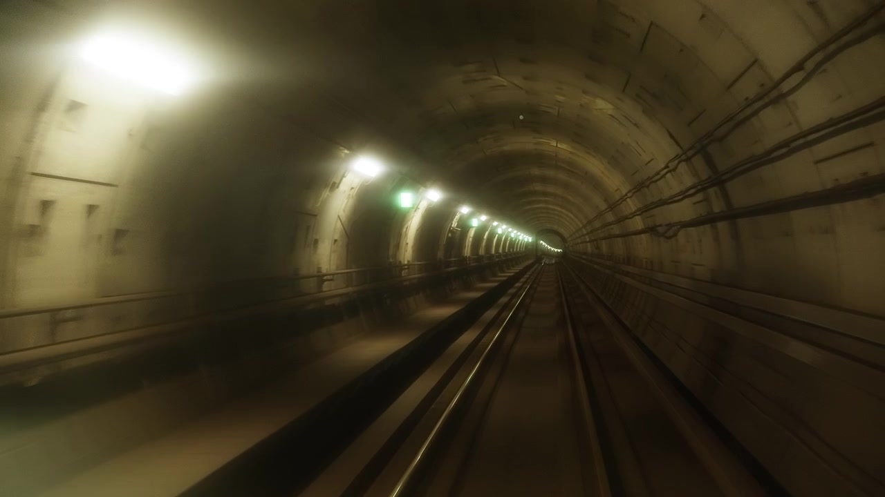 Ripresa POV in movimento in avanti che sfreccia attraverso un moderno tunnel sotterraneo della metropolitana illuminato a Copenaghen, catturando una sfocatura di movimento dinamica lungo i binari ferroviari e le luci in transito
