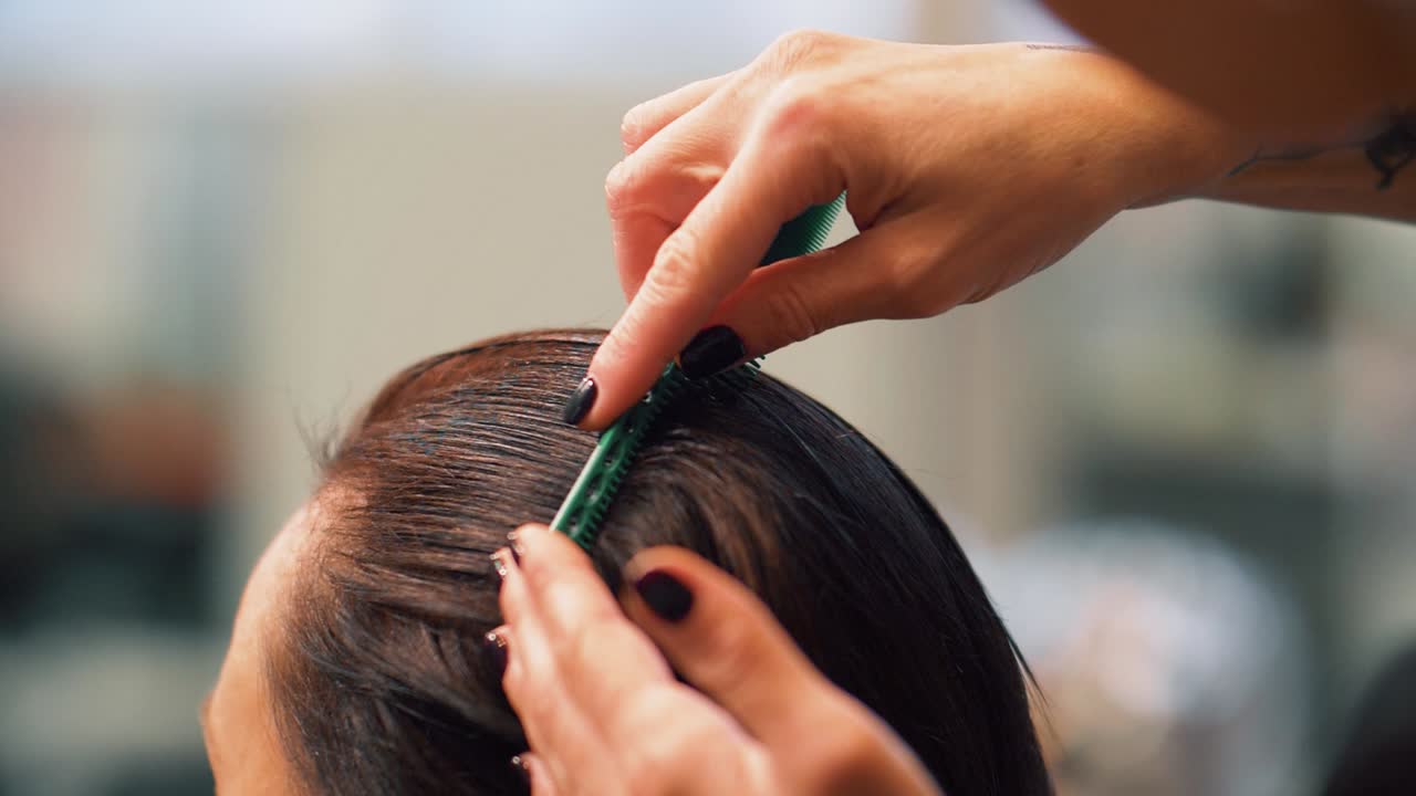 Hairdresser brushing wet hair before trimming ends. Hairstylist combing women hair right after washing.