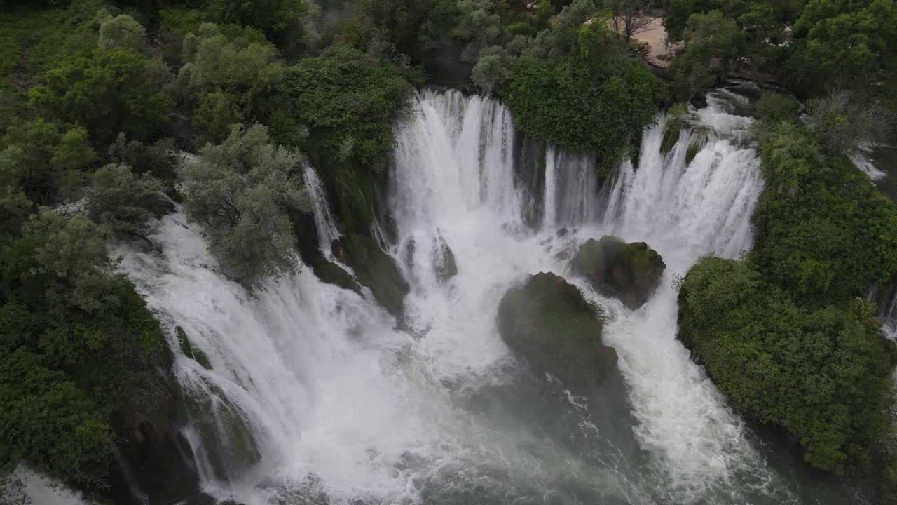 vista desde arriba del agua que fluye a través de los árboles en la cascada de kravica en bosnia, la imagen creada por el rápido flujo de agua