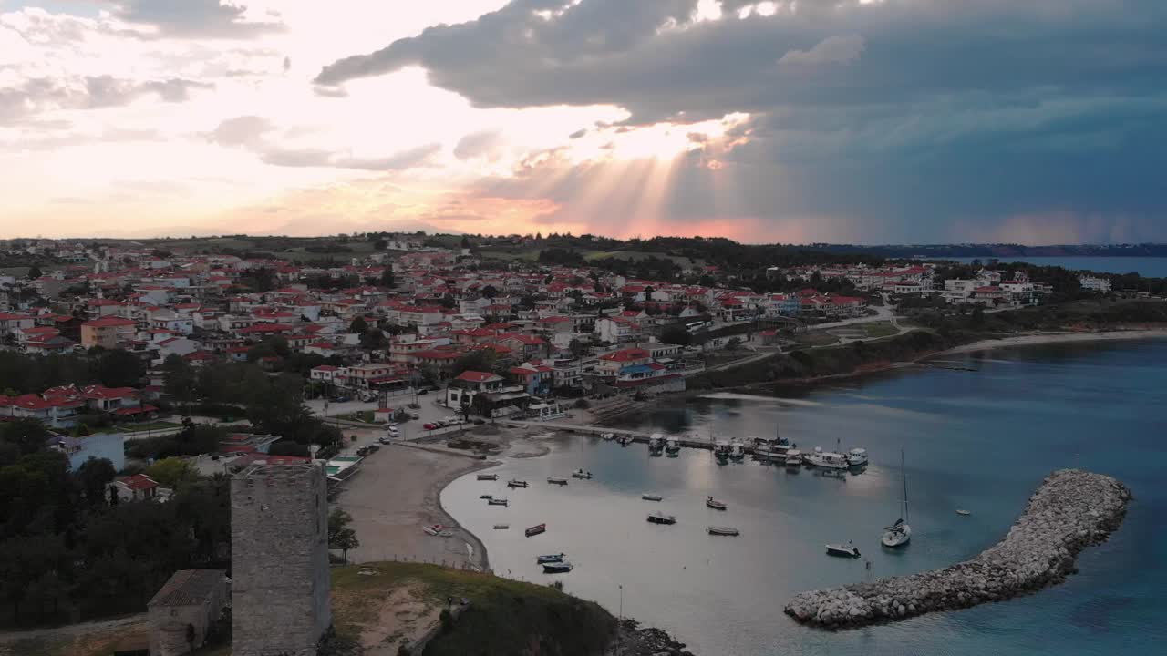 hermosa puesta de sol sobre el puerto deportivo y la torre bizantina en nea fokea, halkidiki, grecia