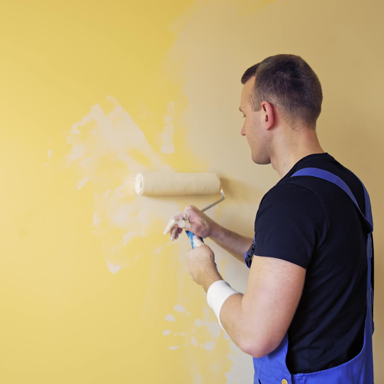 Young worker painting wall in room. Repair, building and home concept
