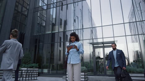 focused woman use tablet in downtown area. diverse employees rush to workplace.