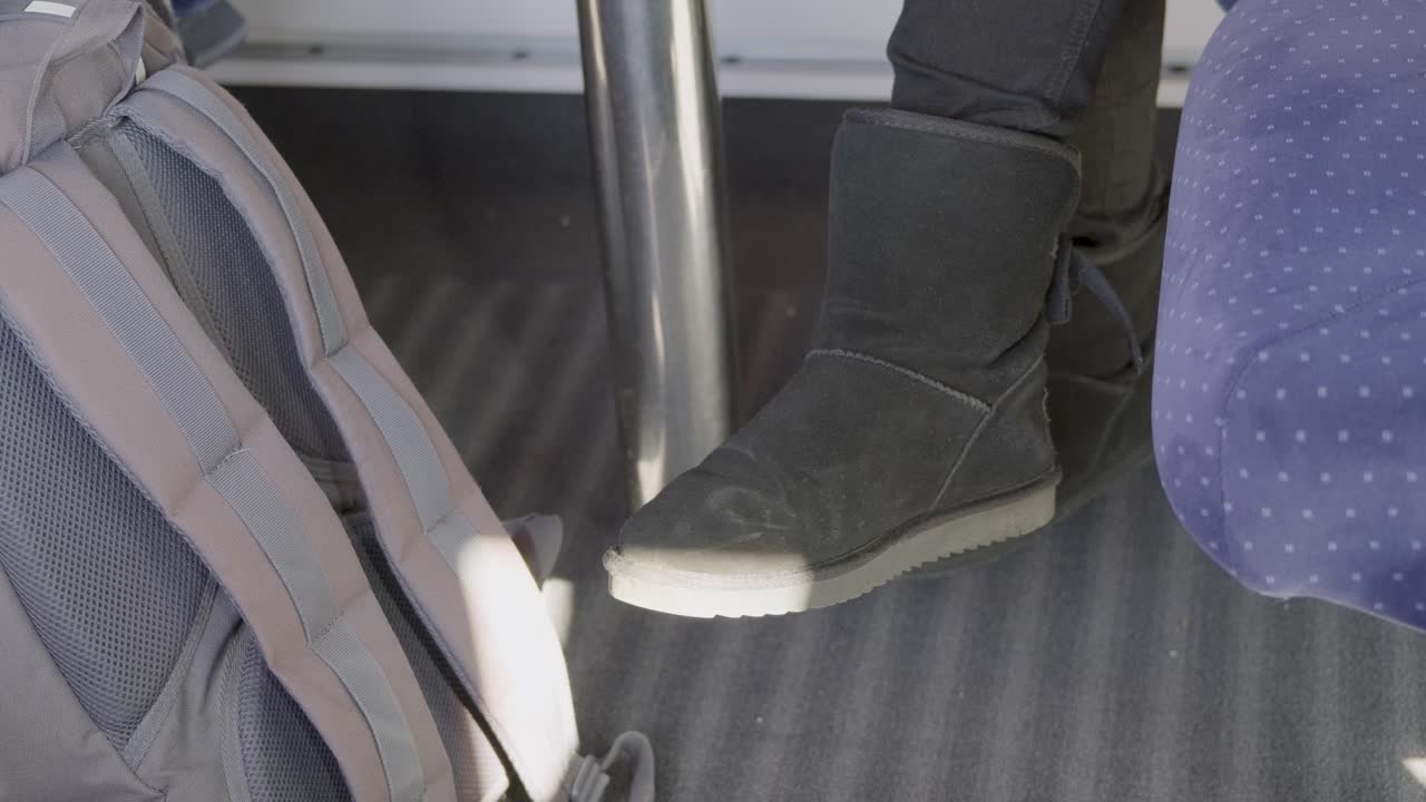 A close-up of a foot wearing black boots in a German ICE high-speed train, with a backpack nearby