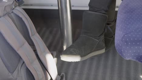 a close-up of a foot wearing black boots in a german ice high-speed train, with a backpack nearby