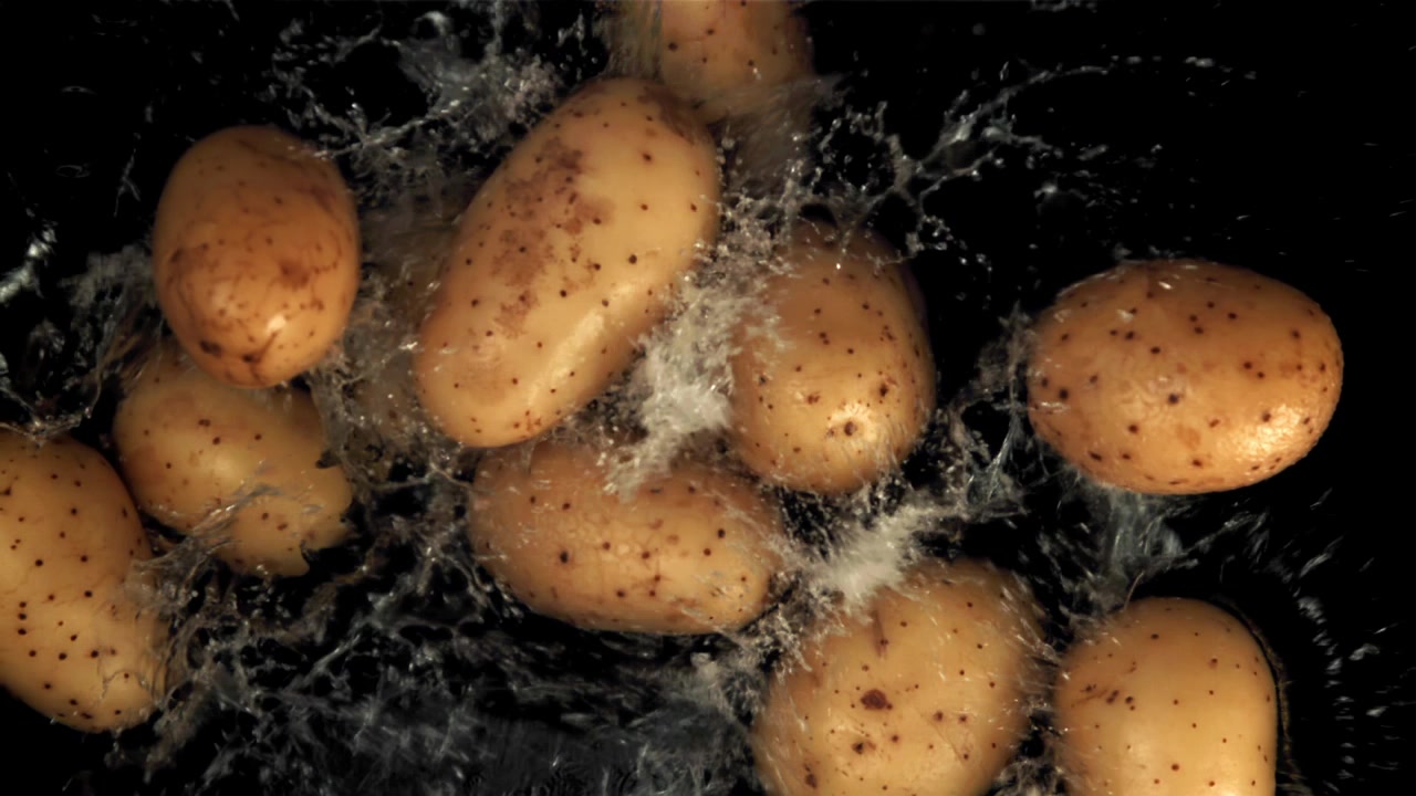 Movimento super rallentato di acqua che schizza su patate crude