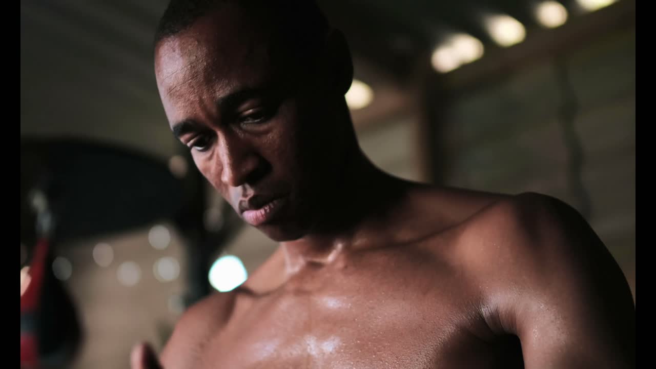 아프리카계 미국인 남성 권투 선수가 피트니스 스튜디오 4k에서 손 포장을 착용하고 있습니다.