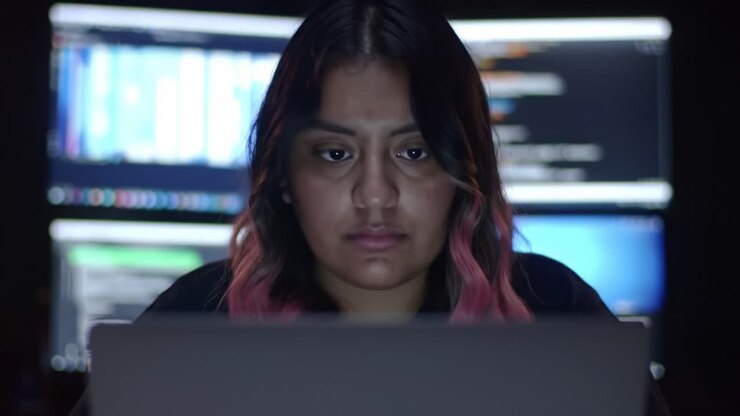 Focused Individual Engaged in Advanced Digital Analysis Amidst Multiple Display Screens Showing Data and Codes in a Dark Environment