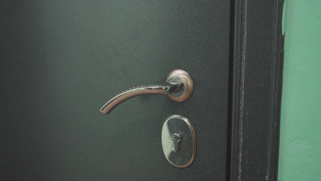 Metal door ajar revealing kitchen scene, shadowed handle and worn lock, warm interior light, hanging utensils blurred, home cook prepping meal beyond door, domestic atmosphere of anticipation