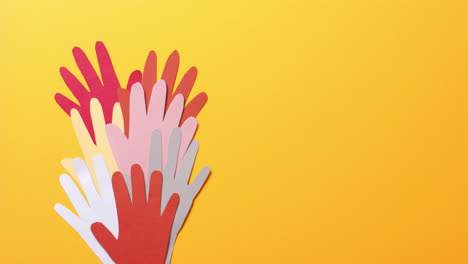cerca de las manos juntas hechas de papel de colores sobre fondo amarillo con espacio para copiar
