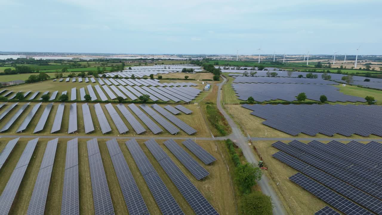 Cinematic drone aerial footage over solar photovoltaic power station and wind turbines generating green energy Yelvertoft Lutterworth England