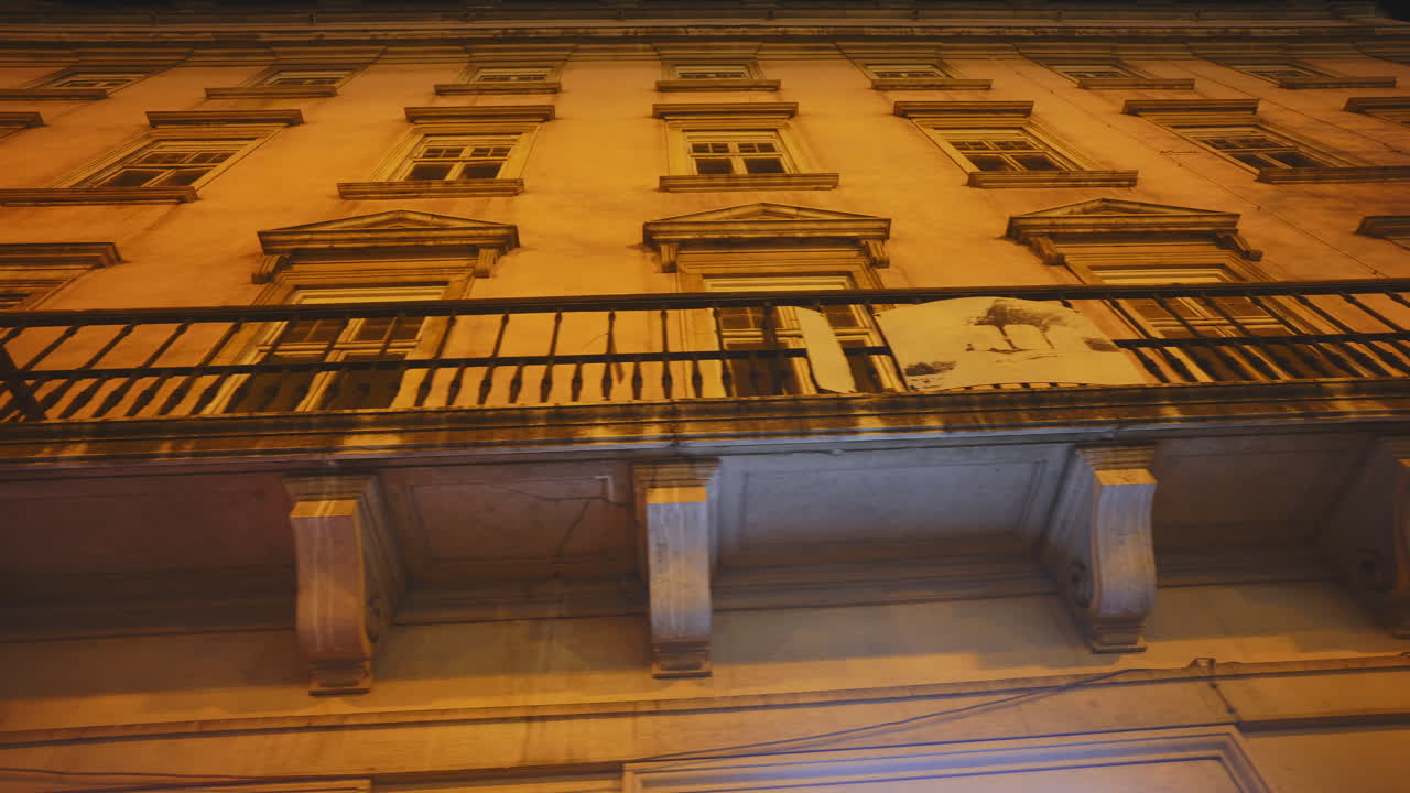 Panoramica verso l'alto della facciata di un vecchio edificio cittadino di notte