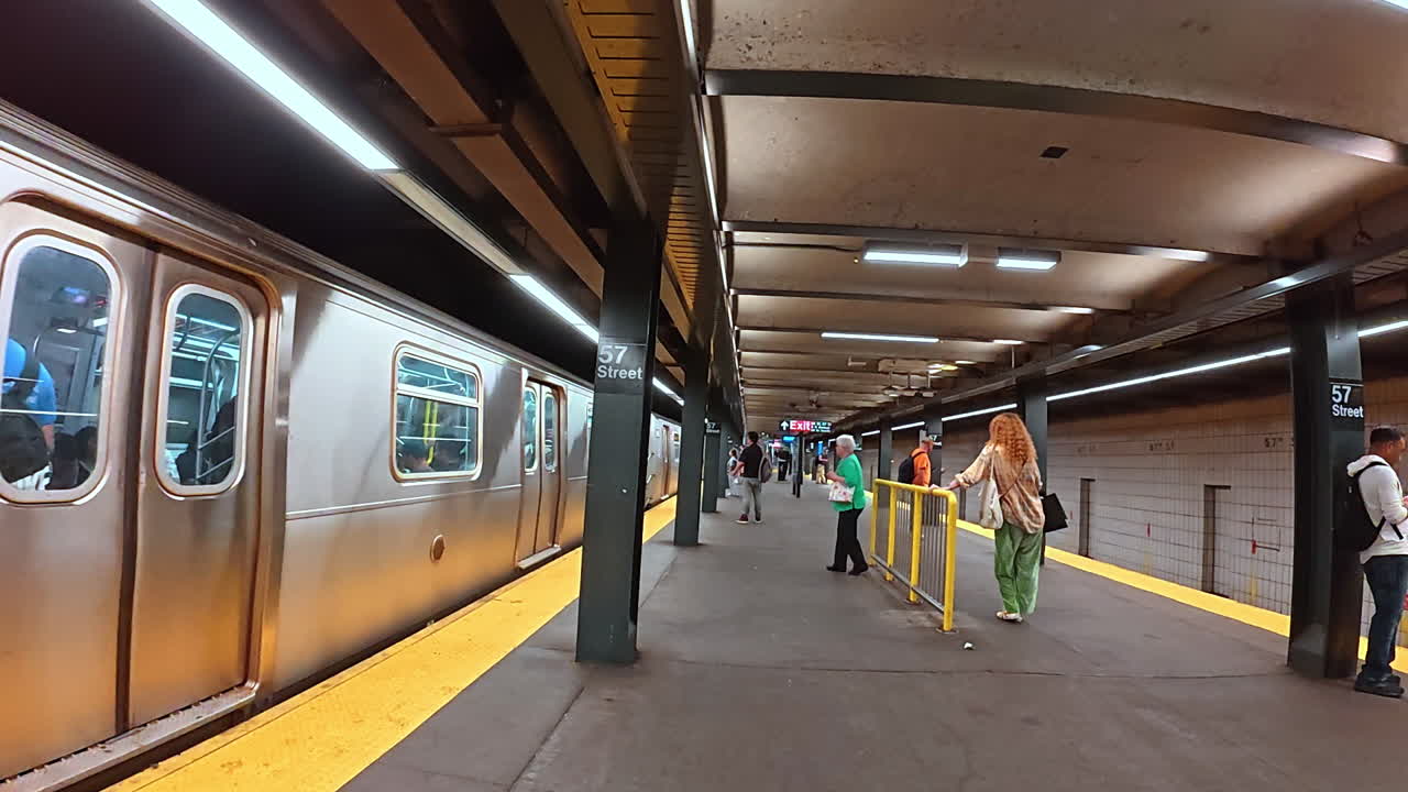 New York, USA, 1 August 2025: Subway train arriving at 57th Street station in New York. An F line subway train pulling into the 57th Street underground station with passengers waiting on the platform