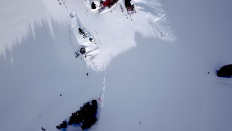 Vista-Aérea-De-La-Estación-De-Esquí-Con-Gente-Haciendo-Snowboard-Cuesta-Abajo