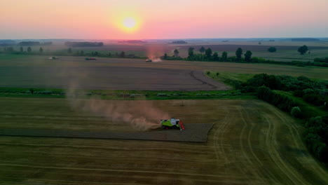 Eine-Drohnenantenne-Dreht-Sich-über-Einem-Traktor,-Der-Pflügt,-Während-Im-Hintergrund-Der-Sonnenuntergang-Untergeht