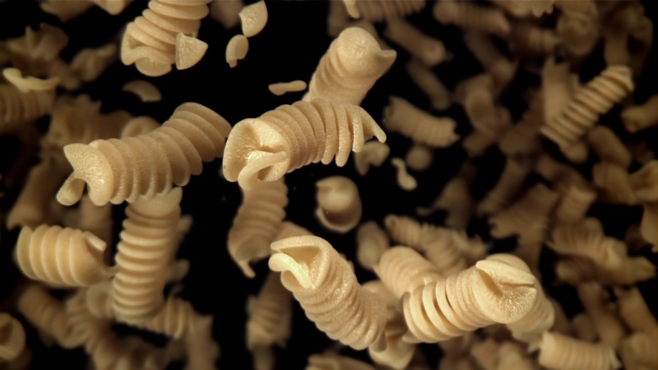 Movimento rallentato di fusilli secchi in caduta su sfondo nero
