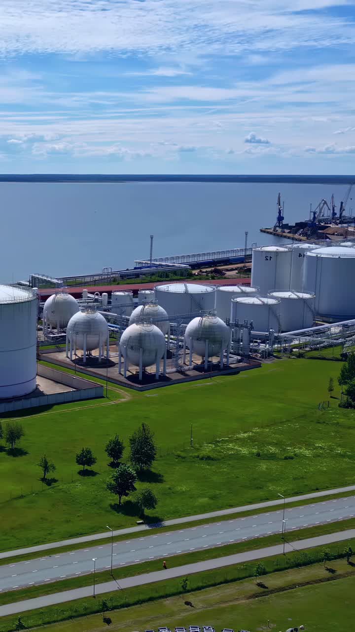 Vertical View Of Multiple Storage Tanks And Port Facilities With Cranes And Ship. Aerial Shot