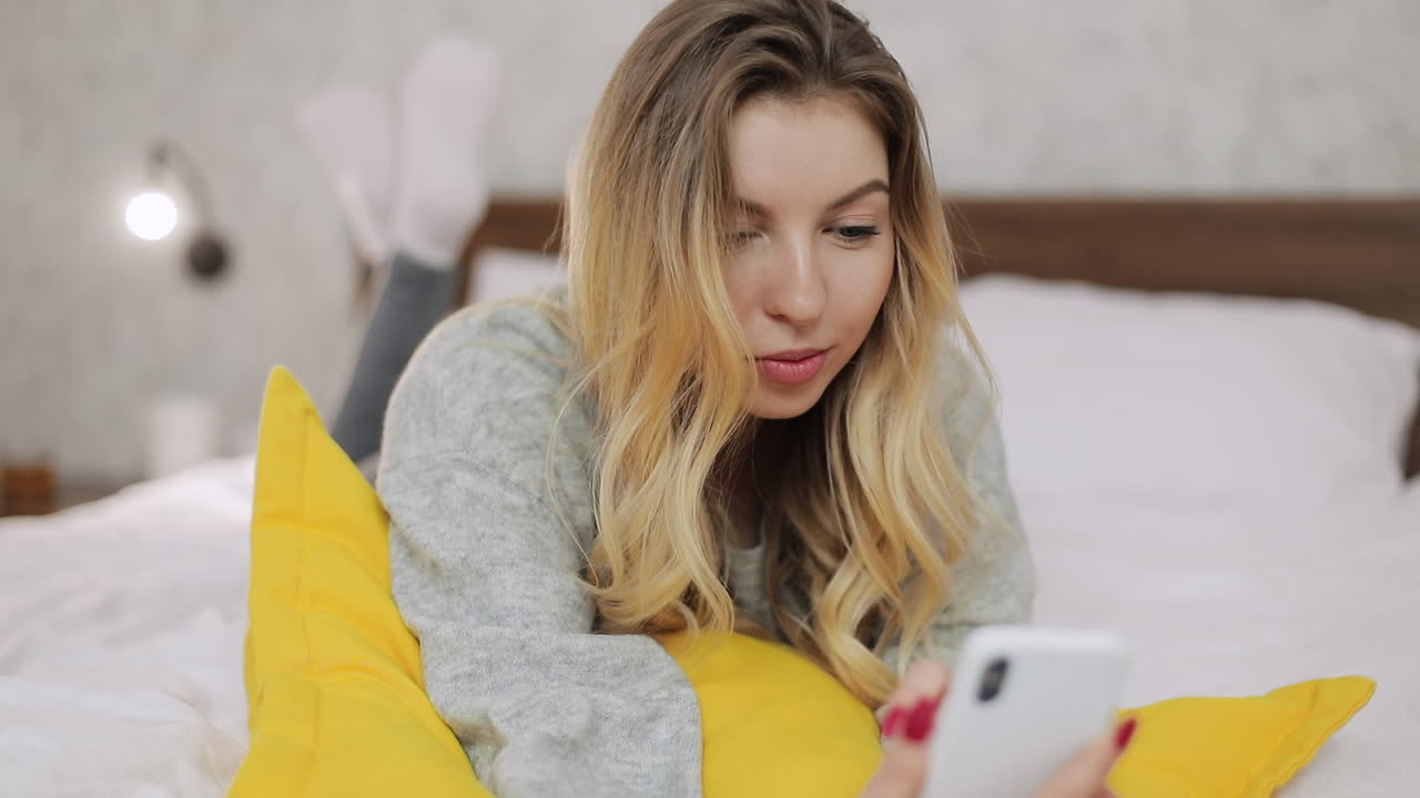 스마트폰으로 침대에서 휴식을 취하는 여자