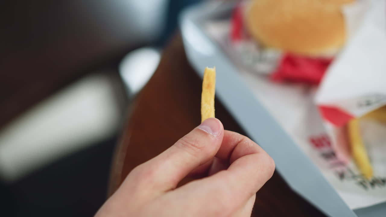 close up view of white hand using thumb and index finger holding thin crispy chip, oil sheen visible, background soft blur, casual snack moment conveying texture appetite and craving