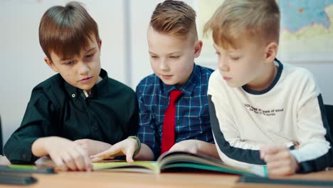 schoolboys in the classroom. children reading a book together in elementary school. education concept.