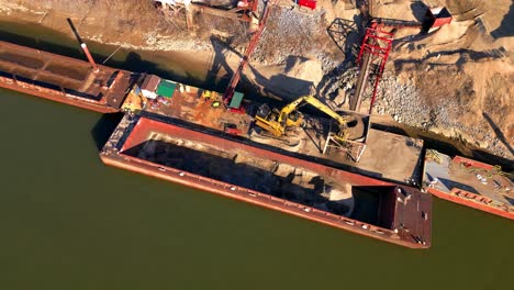 Vista-De-Pájaro-De-La-Excavadora-Descargando-Arena-De-La-Barcaza-En-El-Río-Cumberland-En-Clarksville,-Tennessee