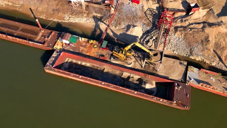 vista de pájaro de la excavadora descargando arena de la barcaza en el río cumberland en clarksville, tennessee