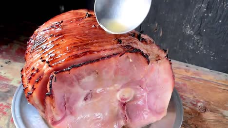 cucharón de jugo sobre jamón cortado en espiral al horno