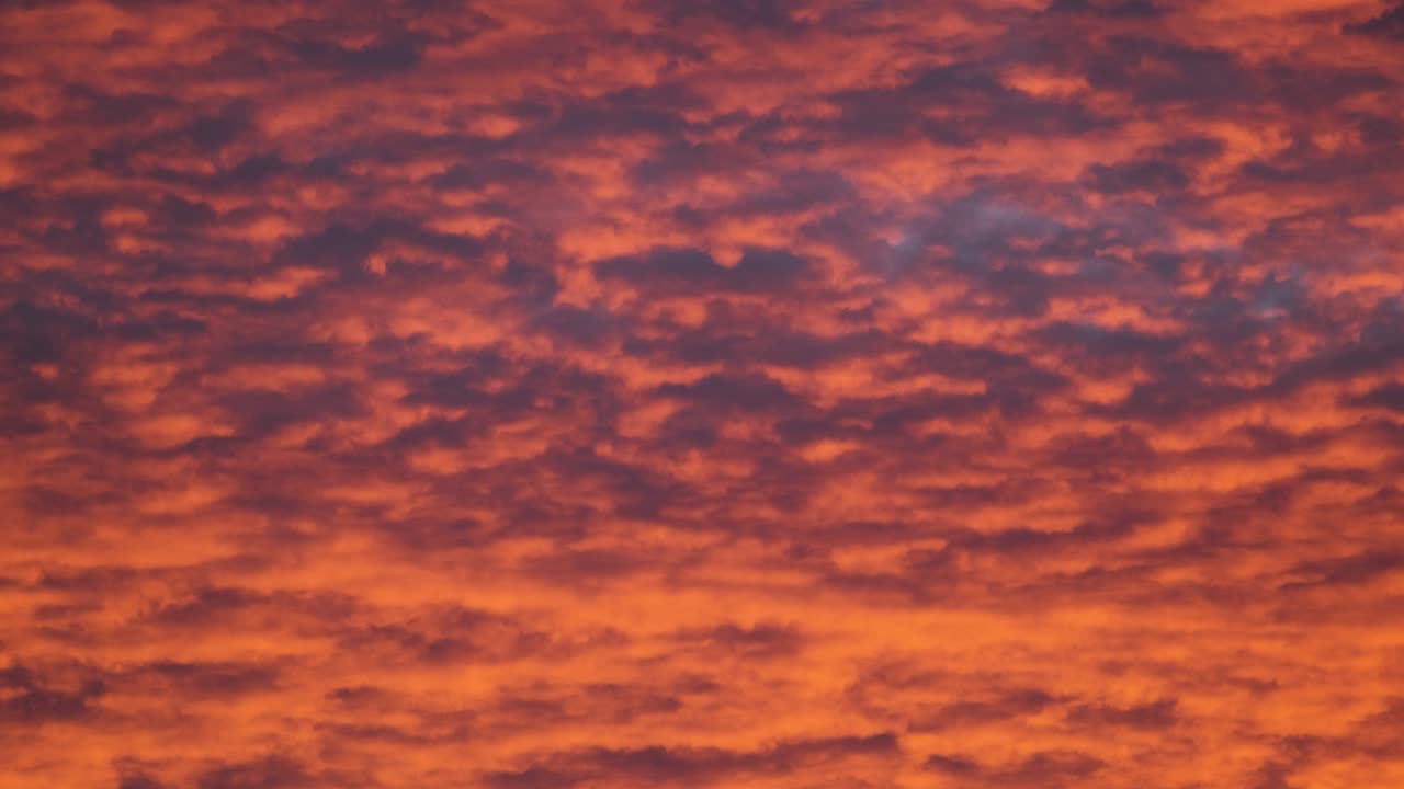 밝고 다채로운 해가 지는 하늘, 생생한 부드러운 구름, 해가 지면으로 퍼지는 빛으로 조명됩니다.