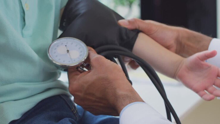 Close Up Of Male Doctor Or GP Examining Boy Taking Blood Pressure With Sphygmomanometer