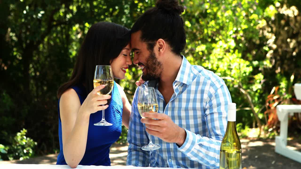 Coppia brinda con bicchieri di vino in ristorante all'aperto 4k