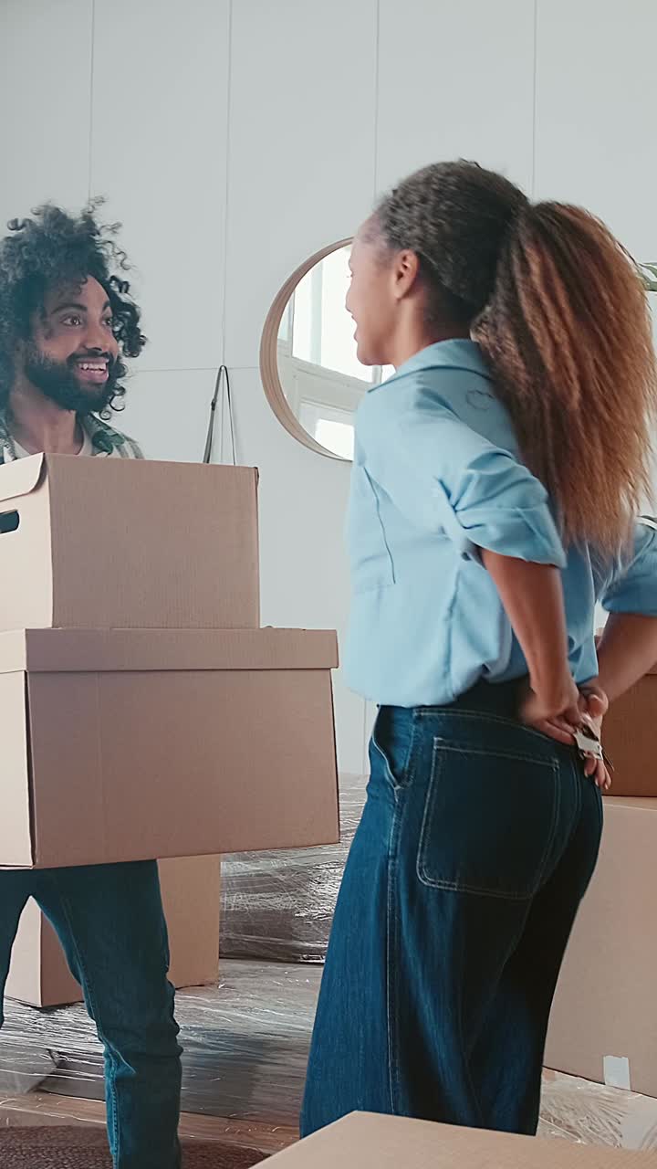 Young happy woman and man property owners dance with boxes and keys in hands