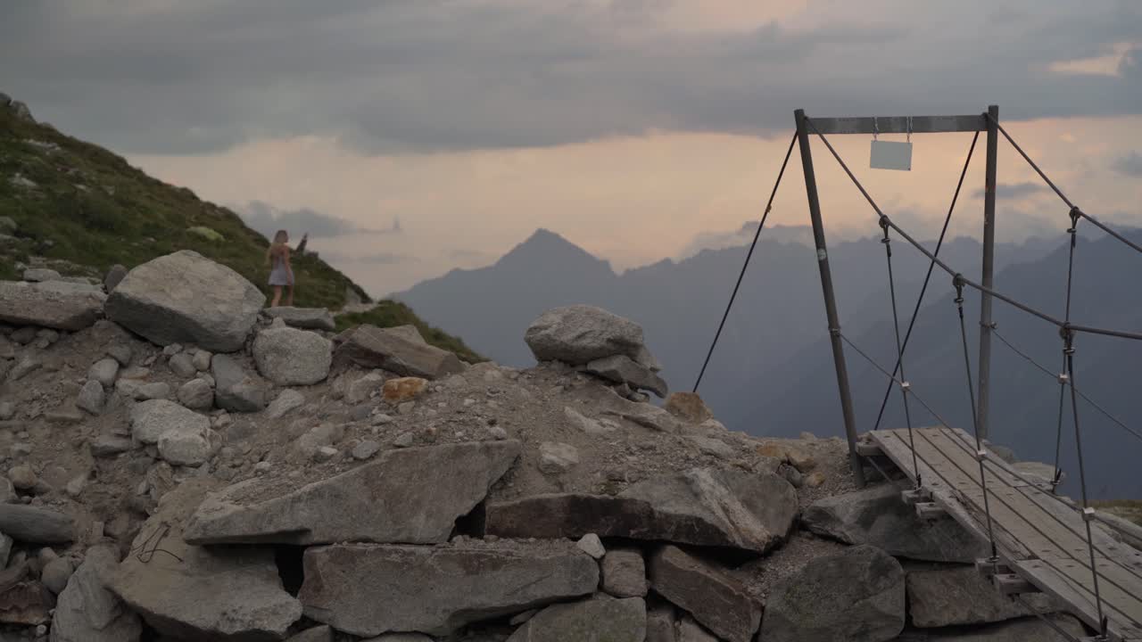 하얀 드레스를 입은 금발 소녀가 산길을 걷고 있다