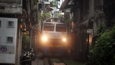 train passing through a narrow alley in vietnam