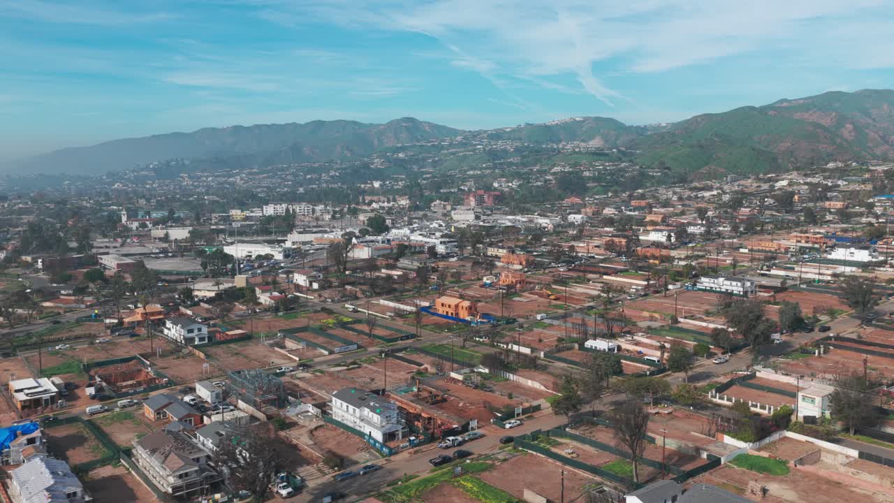 Ripresa aerea con carrello e panoramica di Pacific Palisades durante il processo di ricostruzione un anno dopo gli incendi a Los Angeles, California. 4K