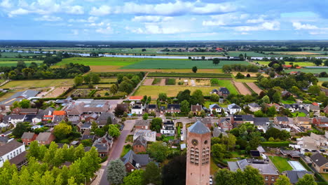 aerial view of dutch countryside. aerial view of green fields, charming homes, and a tower under a vibrant sky in the countryside
