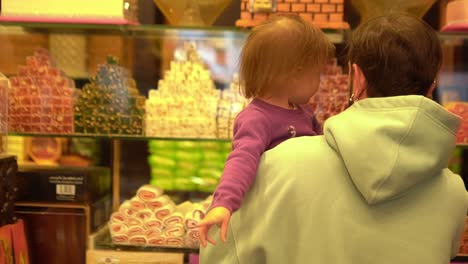 little girl is choosing sweets with dad in candy shop